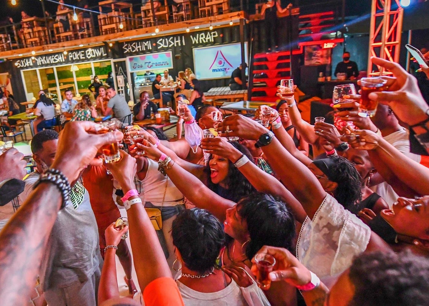 Guests on a Chogogo Party Bus tour raising shot glasses in a toast at an Aruba nightlife stop.